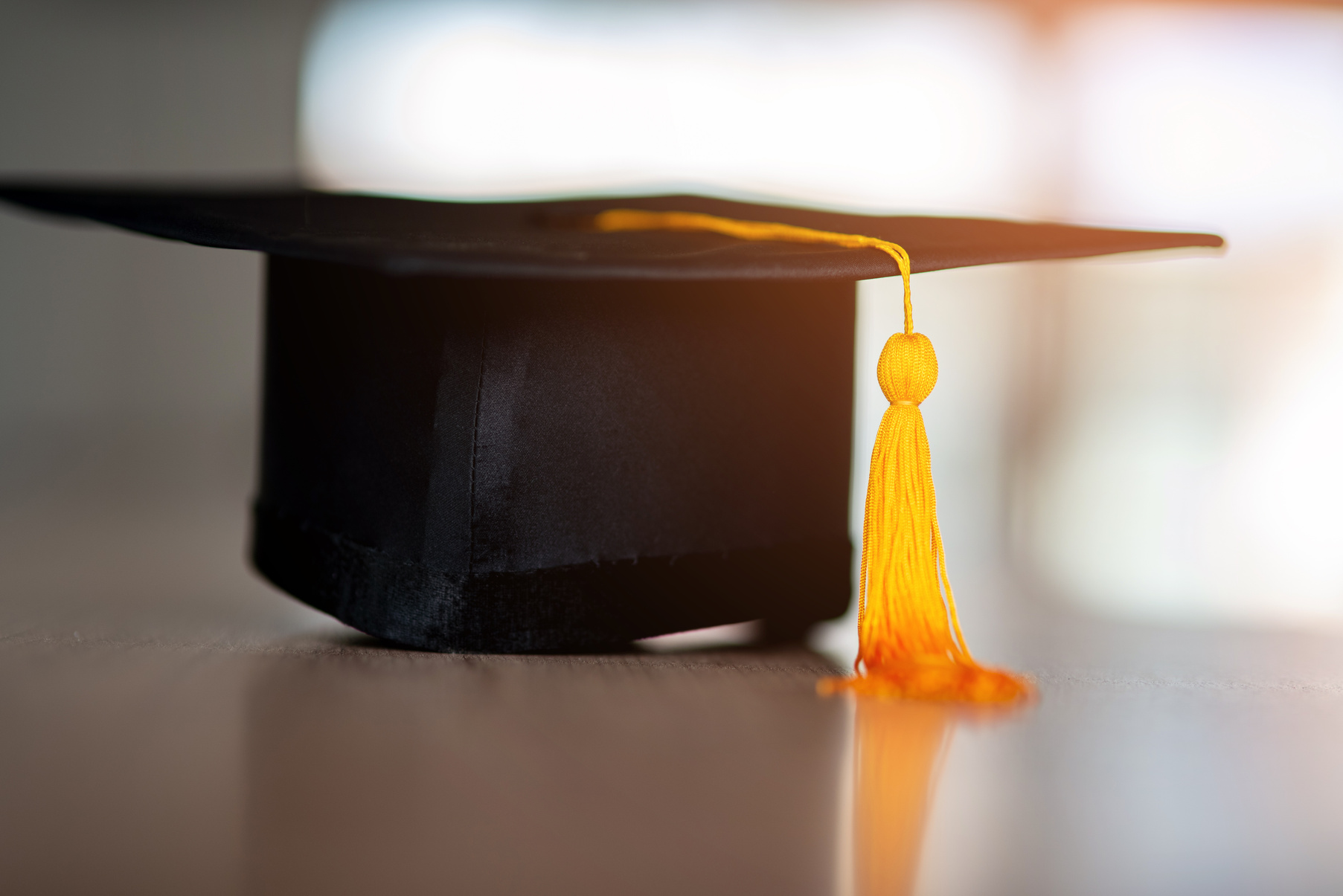 Black hat and yellow tassel of graduates placed on a wooden table